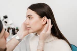 Doctor examining woman’s ears for potential otoplasty